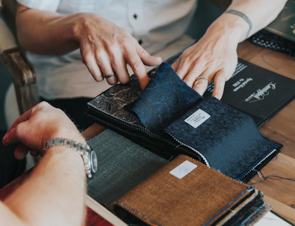 A designer and manufacturer discussing fabric swatches and sketches in a bright studio.