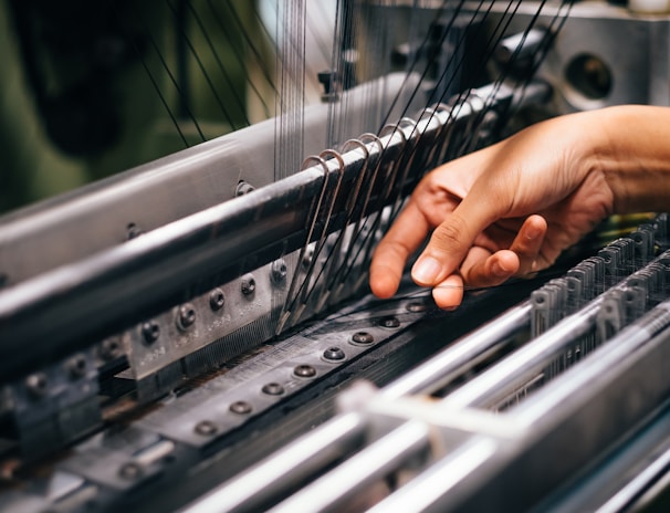 A skilled artisan operating computerized embroidery machinery stitching a delicate design on a garment.
