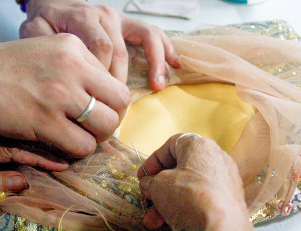 Hands carefully stitching a garment, highlighting the craftsmanship behind each piece.