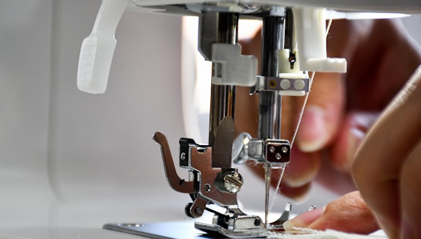 Close-up of skilled hands sewing fabric on a professional sewing machine.