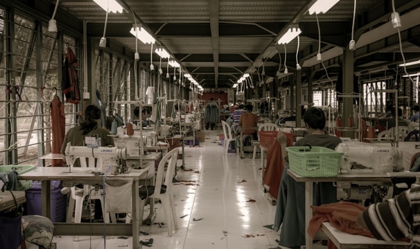 Rows of freshly sewn garments hanging ready for quality inspection in a bright, clean workshop.