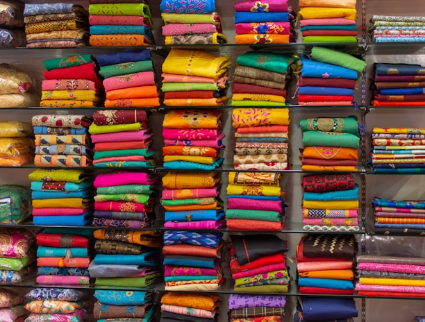 A small batch of colorful, hand block printed garments neatly arranged on a wooden table.