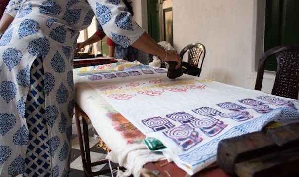 A skilled artisan hand-block printing a fabric with traditional Jaipur patterns.