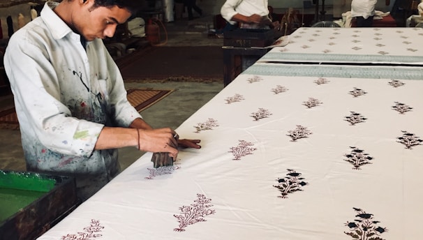 Artisan applying vibrant hand block prints on fabric in a Jaipur workshop.