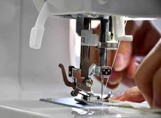 Close-up of skilled hands sewing fabric on a professional sewing machine.