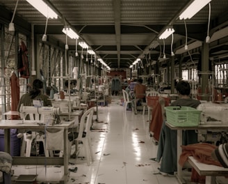 Rows of freshly sewn garments hanging ready for quality inspection in a bright, clean workshop.
