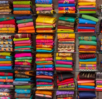 A small batch of colorful, hand block printed garments neatly arranged on a wooden table.