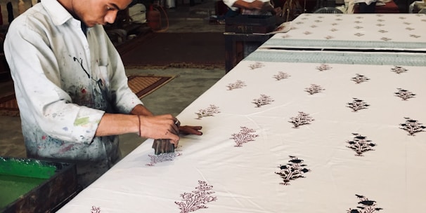 Artisan applying Jaipur hand block prints on fabric in a bright workshop.