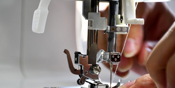 Close-up of skilled hands working on computerized embroidery machine.